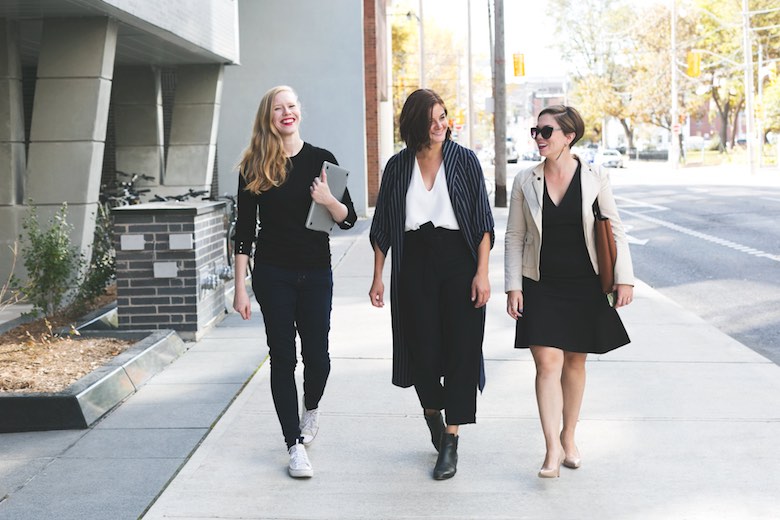 tres mujeres casuales de negocios caminando al trabajo y sonriendo